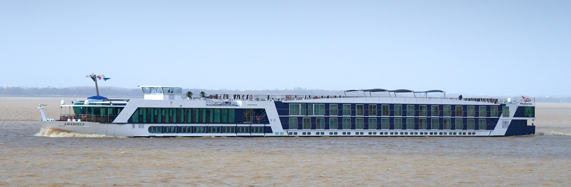 AmaDolce river cruise ship sailing through the Bordeaux wine region along the Garonne River at golden hour