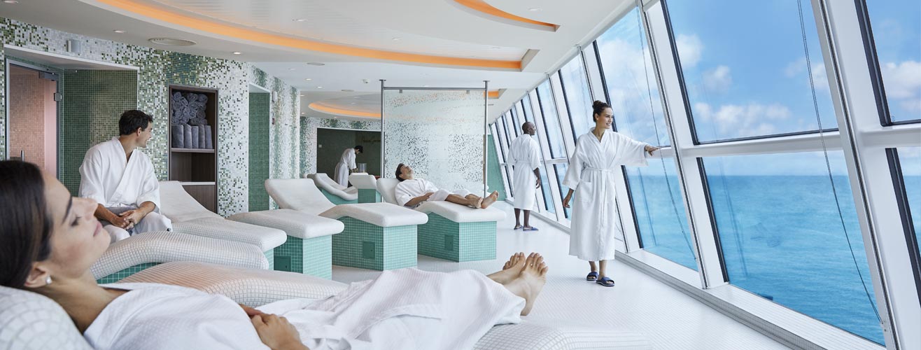 People relaxing in bath robes in a spa room with a sea view