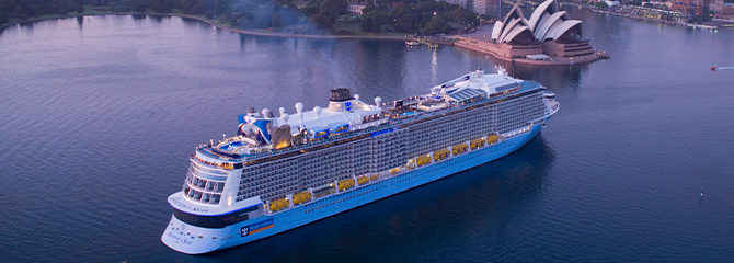 Royal Ovation ship on the water with city in background at dusk